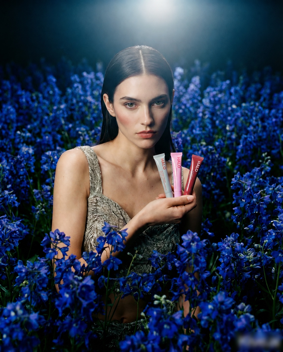 Woman holding Halo lip treatments among deep blue flowers